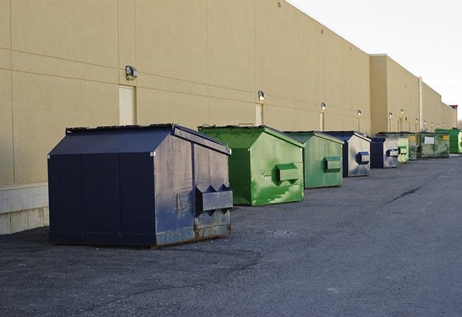 a row of yellow and blue dumpsters at a construction site in Avon